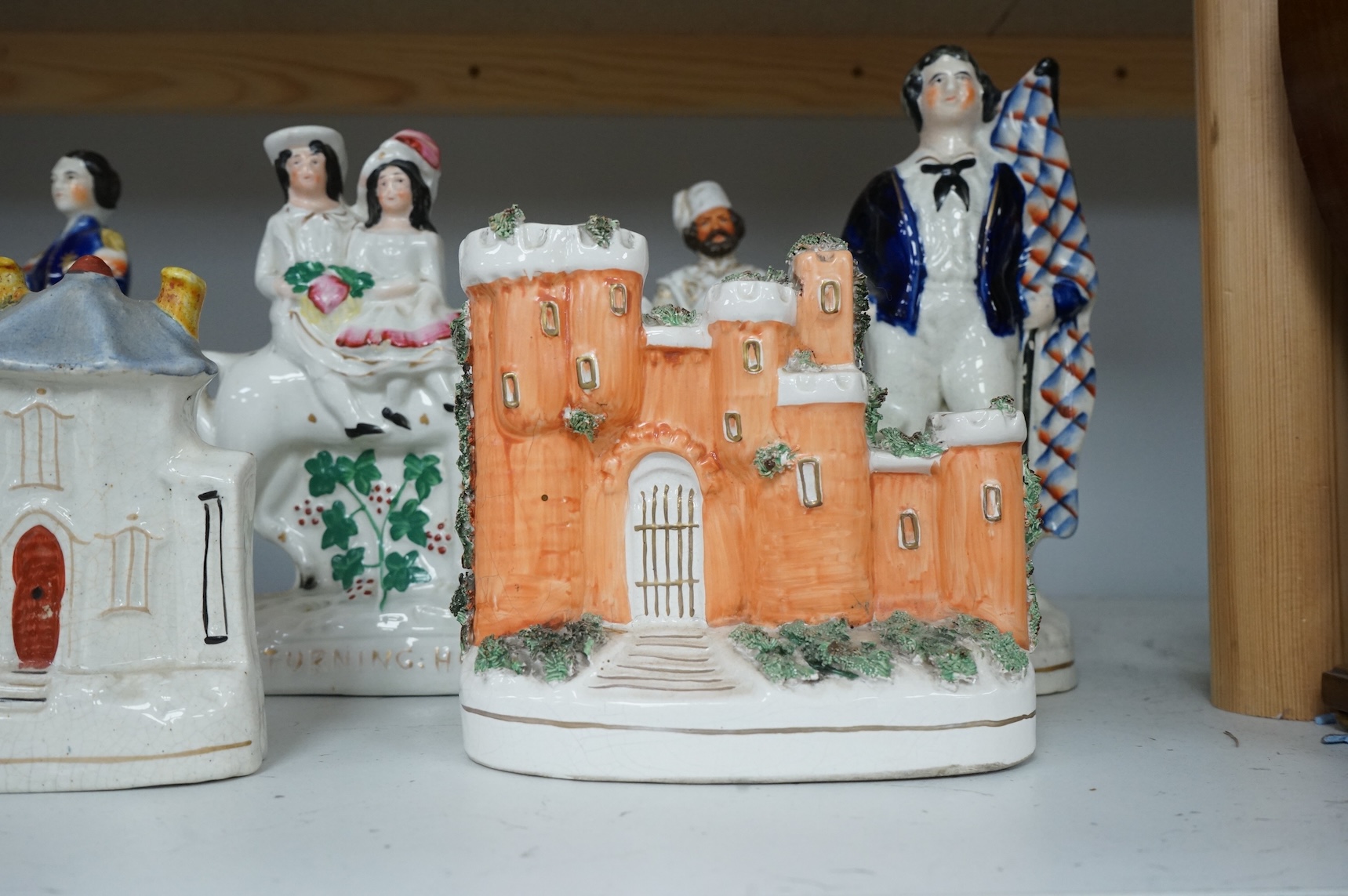 A mid 19th century Paris porcelain figure of a Turkish soldier and six pieces of staffordshire including ‘The Death of Nelson’ group, a 19th century British sailor, ‘Returning Home’ group, and three buildings, tallest 23